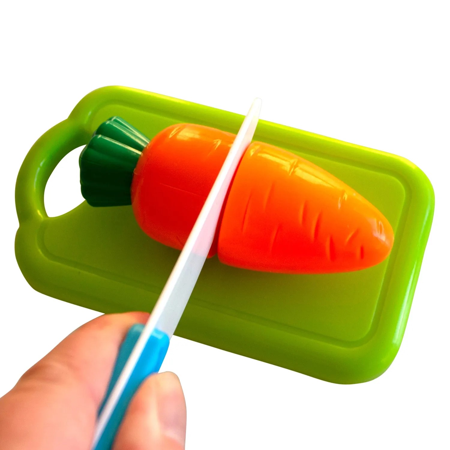 Spielzeug-Karotte wird auf einem grünen Schneidebrett mit einem Messer geschnitten.