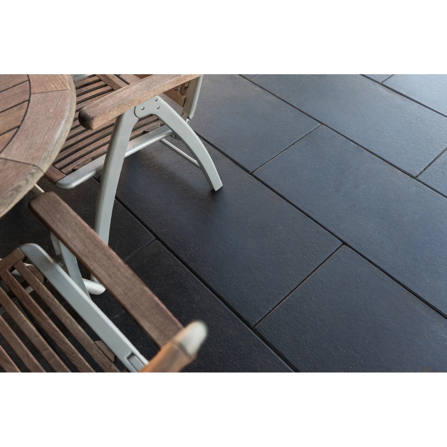 Diephaus Terrassenplatten Finessa in Schwarz-Basalt (80x40) auf Terrasse mit Gartenmöbeln.