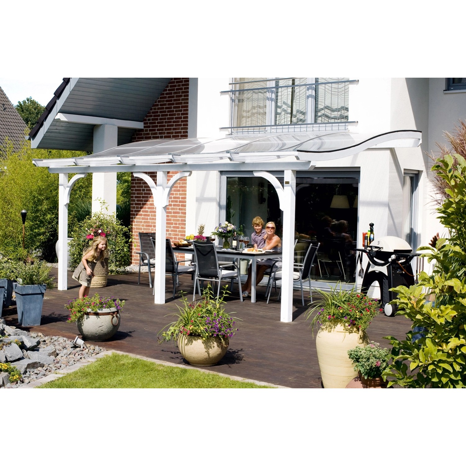 Weiße Skan Holz Terrassenüberdachung Venezia mit Familie beim Essen im Garten.