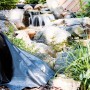 Schwarze Heissner PVC Teichfolie (6x6m) am Teich mit Wasserfall im Garten.