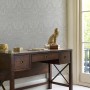 Laura Ashley Vliestapete Heraldic Damask in Grau an Wand hinter Schreibtisch mit Deko.