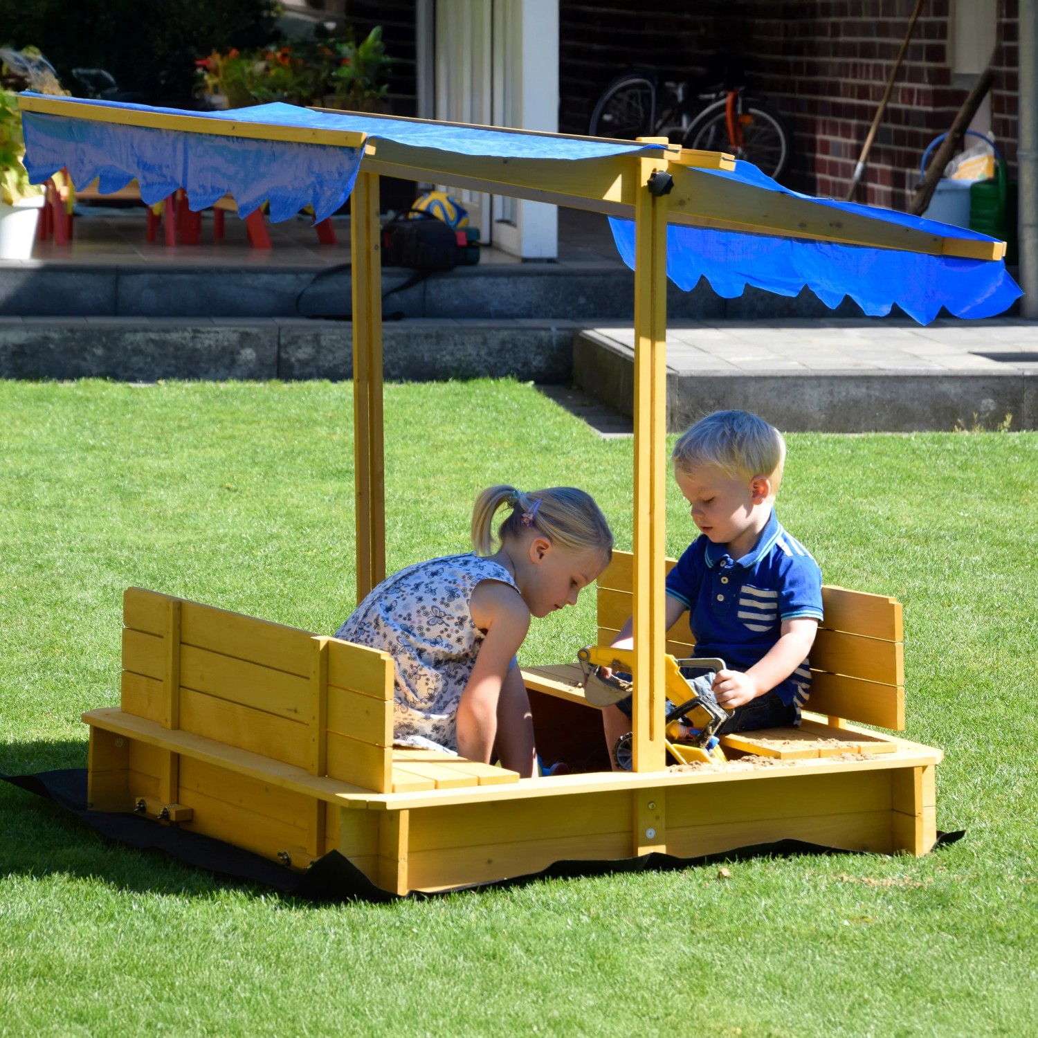 Dobar Sandkasten mit Dach, Kinder spielen im gelben Sandkasten mit blauem Sonnenschutz.