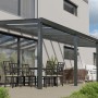 Anthrazitfarbene Terrassenüberdachung Basic mit Glasdach, 700x250 cm, montiert an Hauswand.