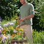 Mann bewässert Blumen mit Gardena Premium Reinigungsspritze im Garten.