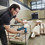 Mann sägt Holz mit Bosch Professional Akku-Stichsäge GST 12 V-70 in Werkstatt. Präzise Schnitte für Holzbearbeitung.