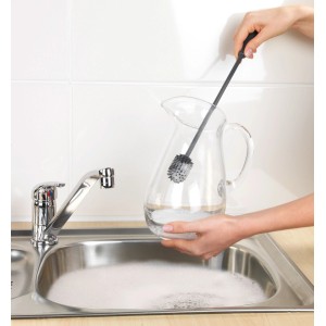 Anthrazitfarbene Wenko Silikon Flaschenbürste (38 cm) reinigt eine Glaskaraffe in der Spüle.