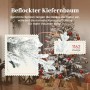 Beflockter künstlicher Weihnachtsbaum in Kiefernform, geschmückt mit roten und goldenen Kugeln, im Wohnzimmer.
