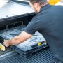 Mann lädt klappbare Stanley FatMax Werkbank in ein Auto. Mobile Werkbank mit Tragegriff.