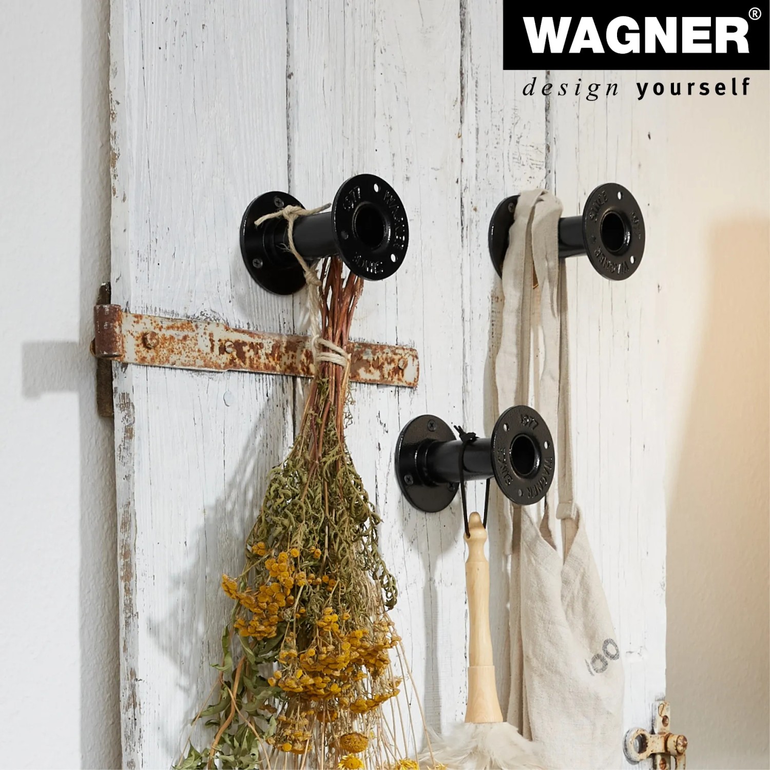 Schwarzes Wagner Möbelbein Industrial Pipe (Länge 100 mm) im Industrial Style an einer weißen Holzwand.
