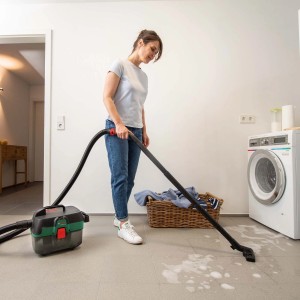 Frau saugt mit Bosch Akkusauger AdvancedVac 18V-8 Flüssigkeit auf. Nass- & Trockensauger mit Zubehör.