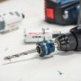 Bosch Power Change Plus System 8,7 mm im Bohrfutter einer Bohrmaschine, Lochsägen im Hintergrund.
