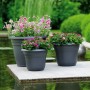 Anthrazitfarbene Florus Pflanztöpfe Fiore Alessia (Ø 55 cm) mit bunten Blumen auf einer Terrasse.
