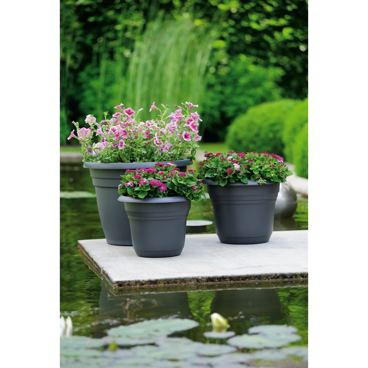 Anthrazitfarbene Florus Pflanztöpfe Fiore Alessia (Ø 55 cm) mit bunten Blumen auf einer Terrasse.