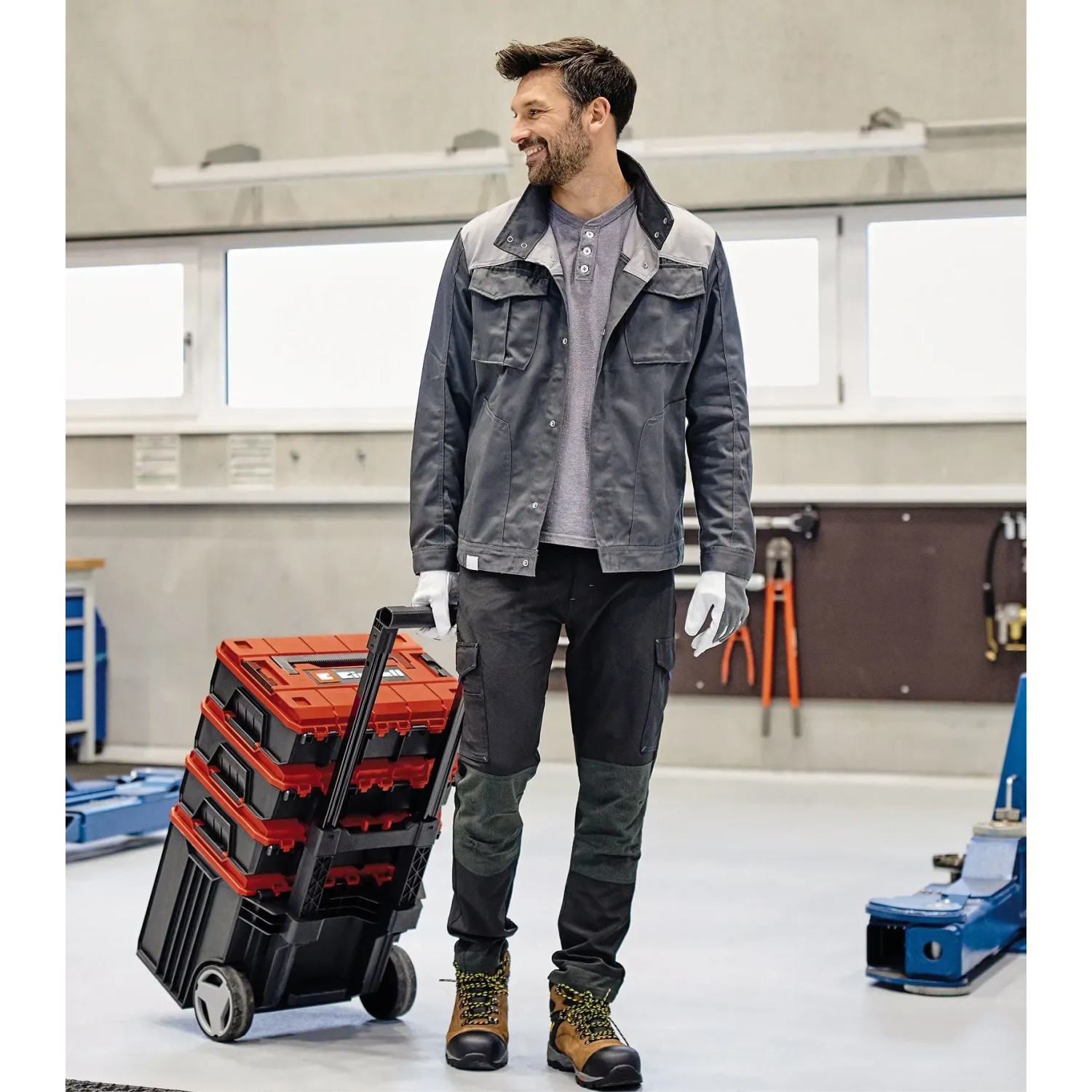 Mann zieht Einhell E-Case L Werkzeugkoffer mit Rollen. Mobiler Werkzeugtransport.