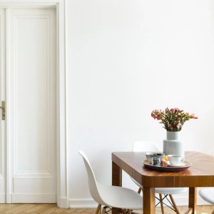 Heller Raum mit weiß gestrichener Wand mit Valspar Innenfarbe Super Weiß und Holztisch mit Blumenvase.