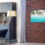 Könighaus Infrarotheizung mit Traumstrand-Motiv an Backsteinwand im Wohnraum.