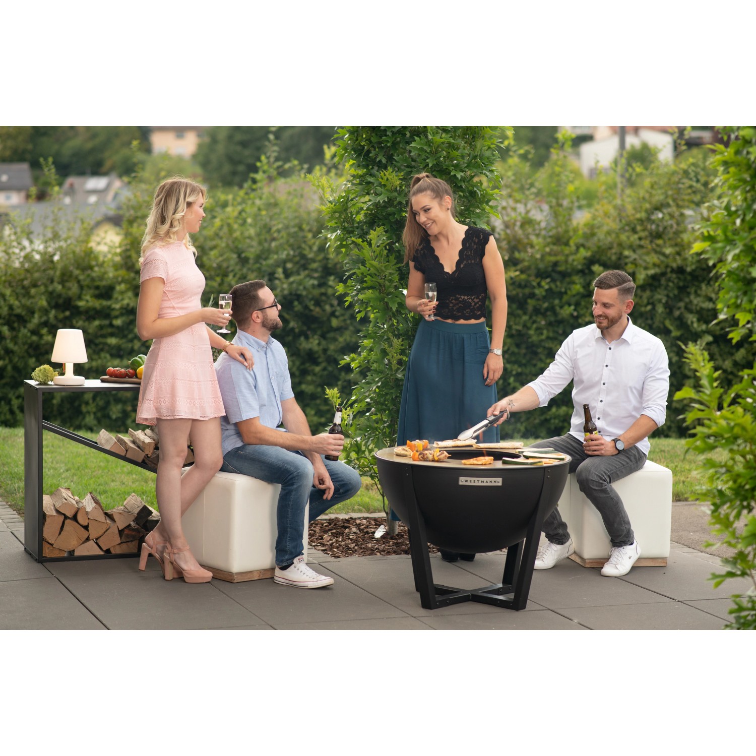 Westmann Premium Grill Feuerstelle, Ø 81cm, schwarz, mit Personen beim Grillen im Garten.