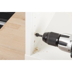 wolfcraft Reparaturset: Bohrer setzt präzises Loch in weiße Korpusseite für Topfscharniere. Möbelreparatur.