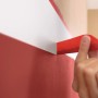 Anwendung von rotem tesa® Malerband Excellent für Farbkanten im Innenbereich.