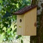 Nistkasten aus Kiefernholz mit Rindendach am Baum befestigt.