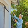 Mann reinigt Fassade mit Gardena Akku-Multi-Reiniger AquaBrush. Inkl. Bürstenaufsatz.