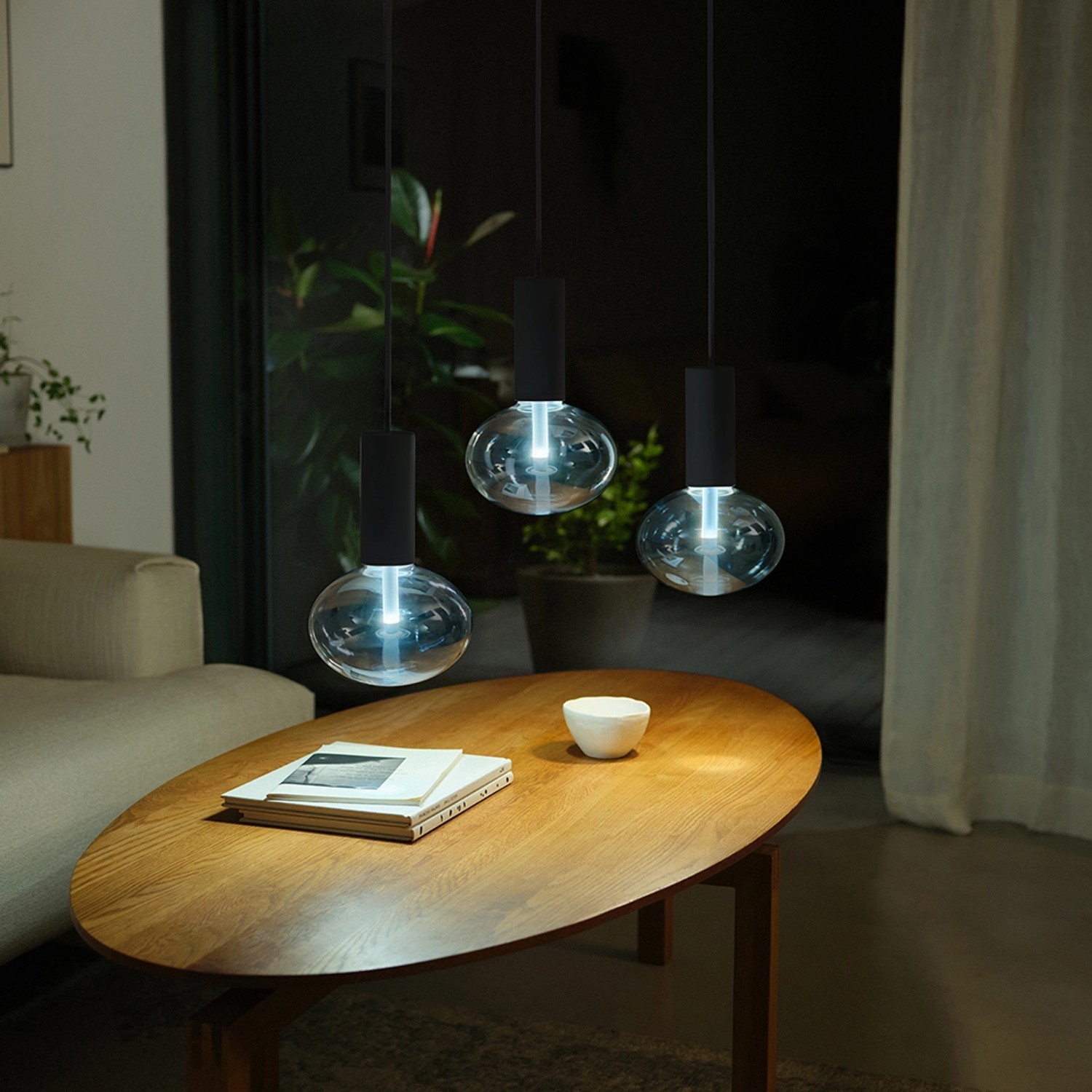 Drei Philips Hue E27 LED Lampen Lightguide Ellipse über einem Tisch. Smarte Lampe mit Farbwechsel.