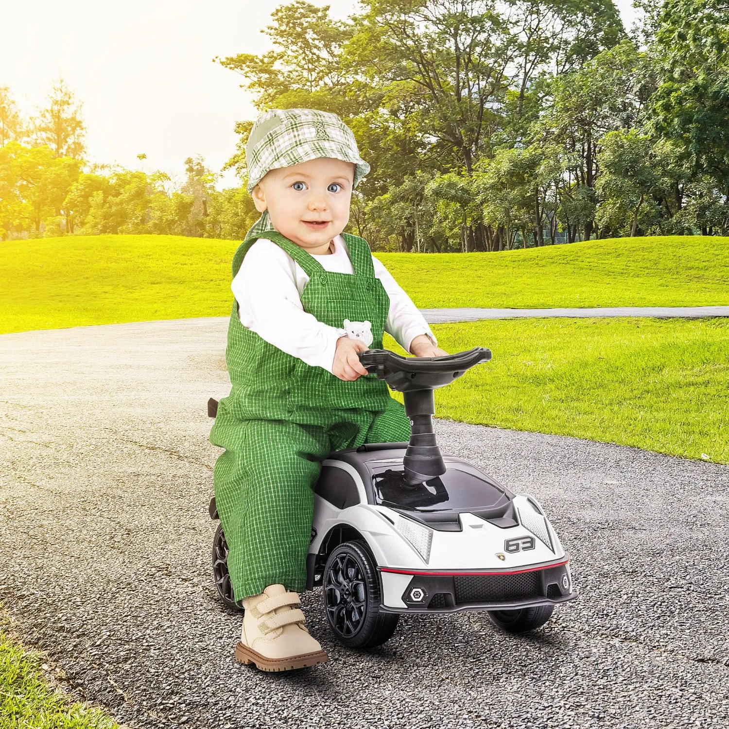 Lächelndes Kleinkind in grünem Overall auf weiß-schwarzem AIYAPLAY Rutschauto im Park.