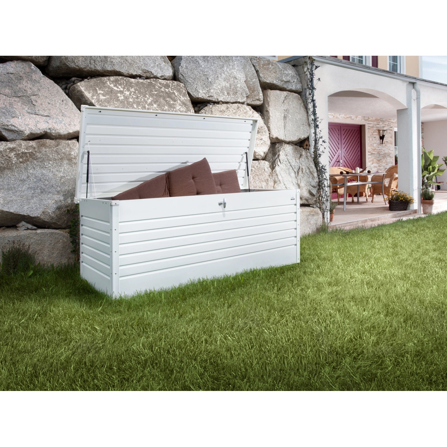 Geöffnete, weiße Biohort Freizeitbox Gr. 200 im Garten, gefüllt mit Kissen.