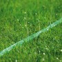 Grüner Gardena Schlauch-Regner 15m im Einsatz auf Rasen, bewässert schmale Gartenbereiche.