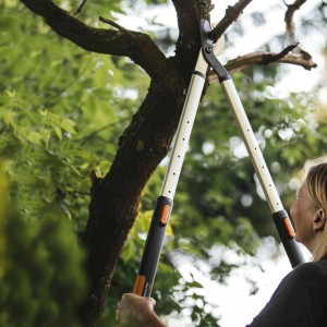 Fiskars SmartFit L86 Teleskop-Astschere beim Schneiden eines Astes im Garten.