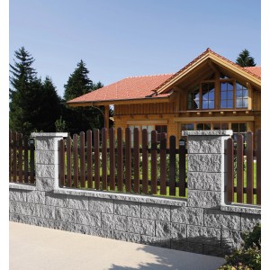 Häusler Alpen Abdeckplatte Nordic Grau auf Mauer mit Holzzaun vor Haus.