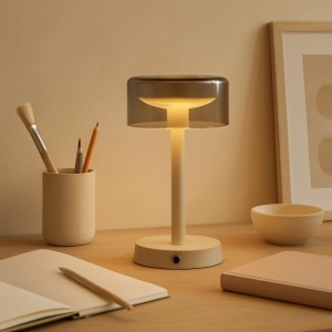 Beige LED-Tischleuchte Razor auf Schreibtisch. Dimmbar, kabellos ladbar. Modernes Design für warmweißes Licht.