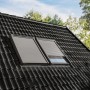 Elektrischer Alu-Rolladen CK04 für Dachfenster, geschlossen auf einem dunklen Ziegeldach.