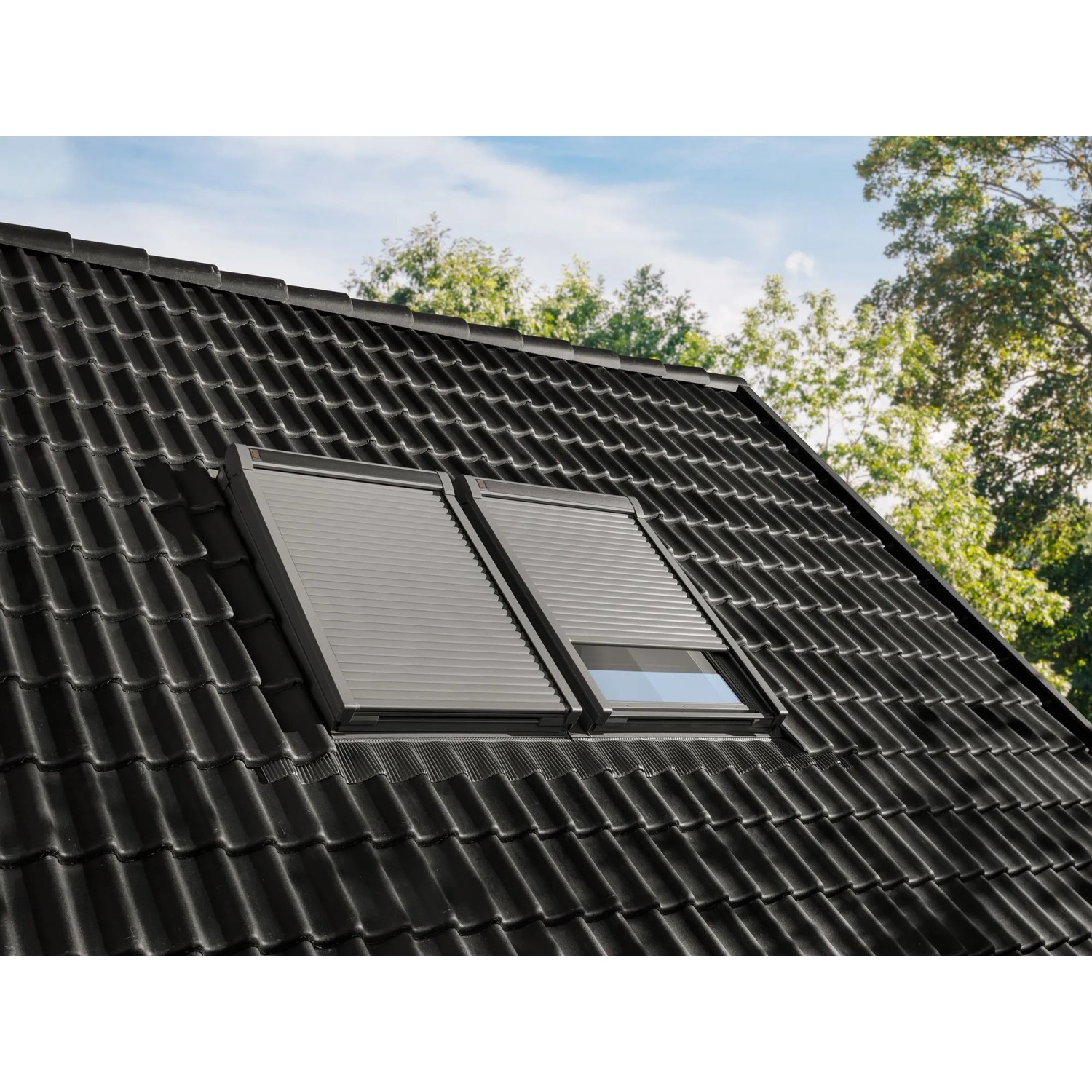 Elektrischer Alu-Rolladen CK04 für Dachfenster, geschlossen auf einem dunklen Ziegeldach.