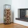 Schwarzes Westmann Kaminholzregal Xavier aus Stahl, gefüllt mit Holzscheiten neben einem Kamin.