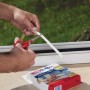 Zuschneiden der weißen Tesamoll Fensterdichtung P-Profil Gummidichtung am Fenster.
