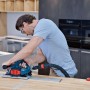 Mann schneidet Holz-Arbeitsplatte mit Bosch Professional Tauchsäge und Führungsschiene. Akku-Betrieb.