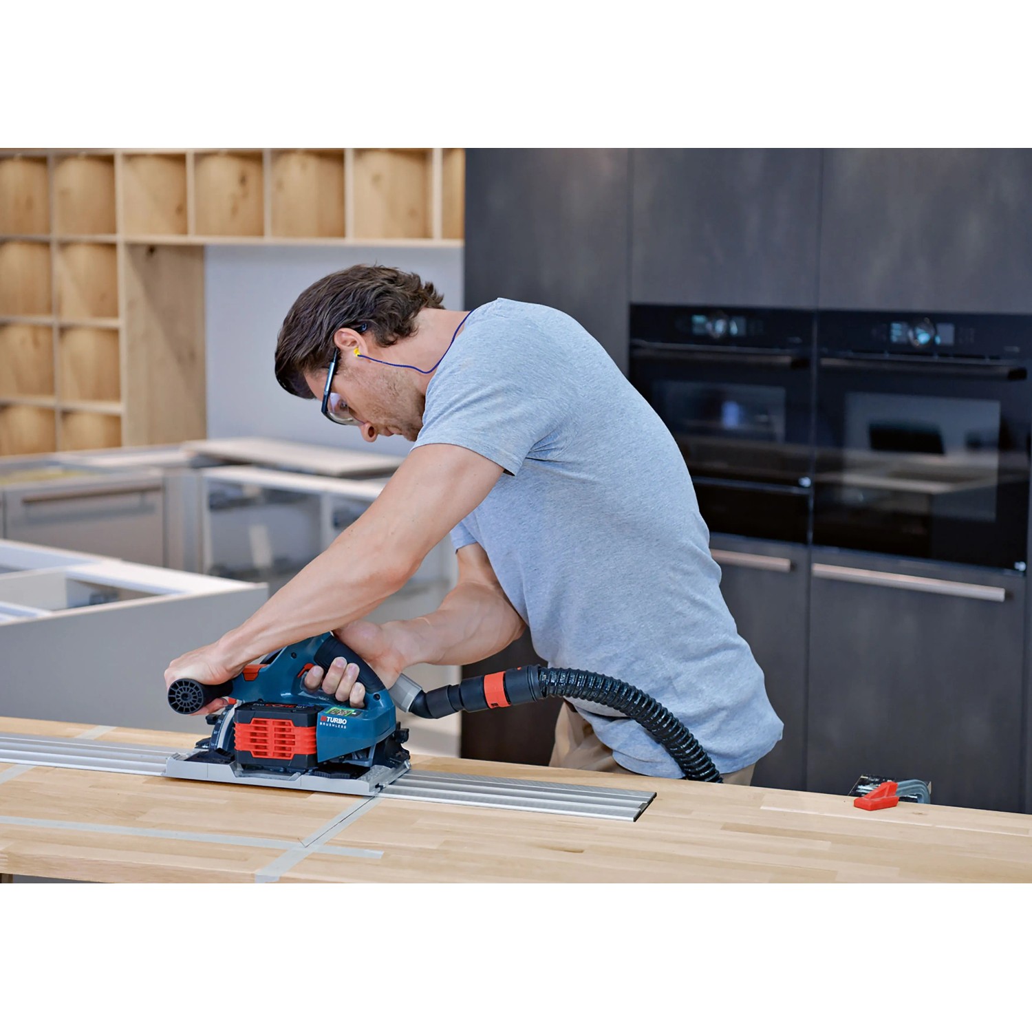 Mann schneidet Holz-Arbeitsplatte mit Bosch Professional Tauchsäge und Führungsschiene. Akku-Betrieb.