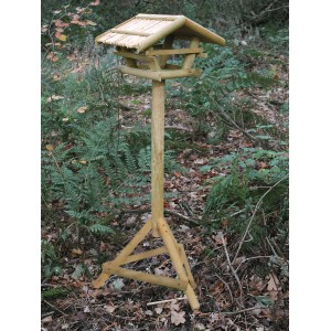 Vogelfutterhaus aus Nadelholz mit Ständer, naturbelassen und mit Schilfdach.