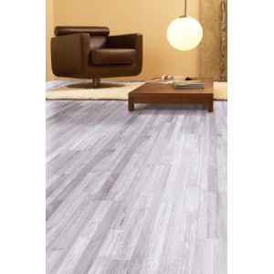 Heller Laminatboden im Pinie Sea Pine Dekor im Wohnraum mit Sessel und Tisch.