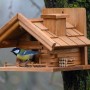 Dobar Vogelhaus St. Moritz im Berghütten-Design mit Vogel auf einem Baumstamm.