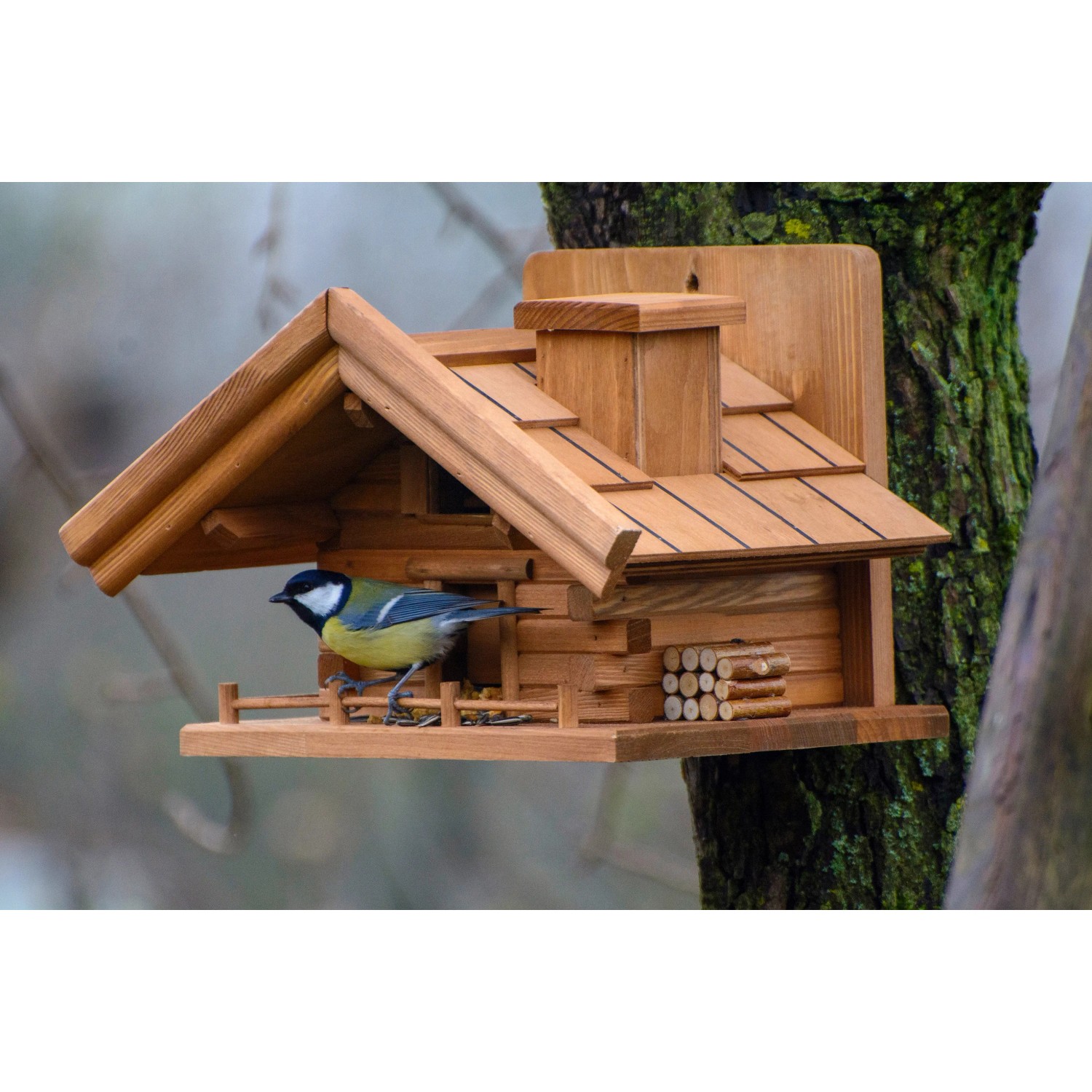 Dobar Vogelhaus St. Moritz im Berghütten-Design mit Vogel auf einem Baumstamm.