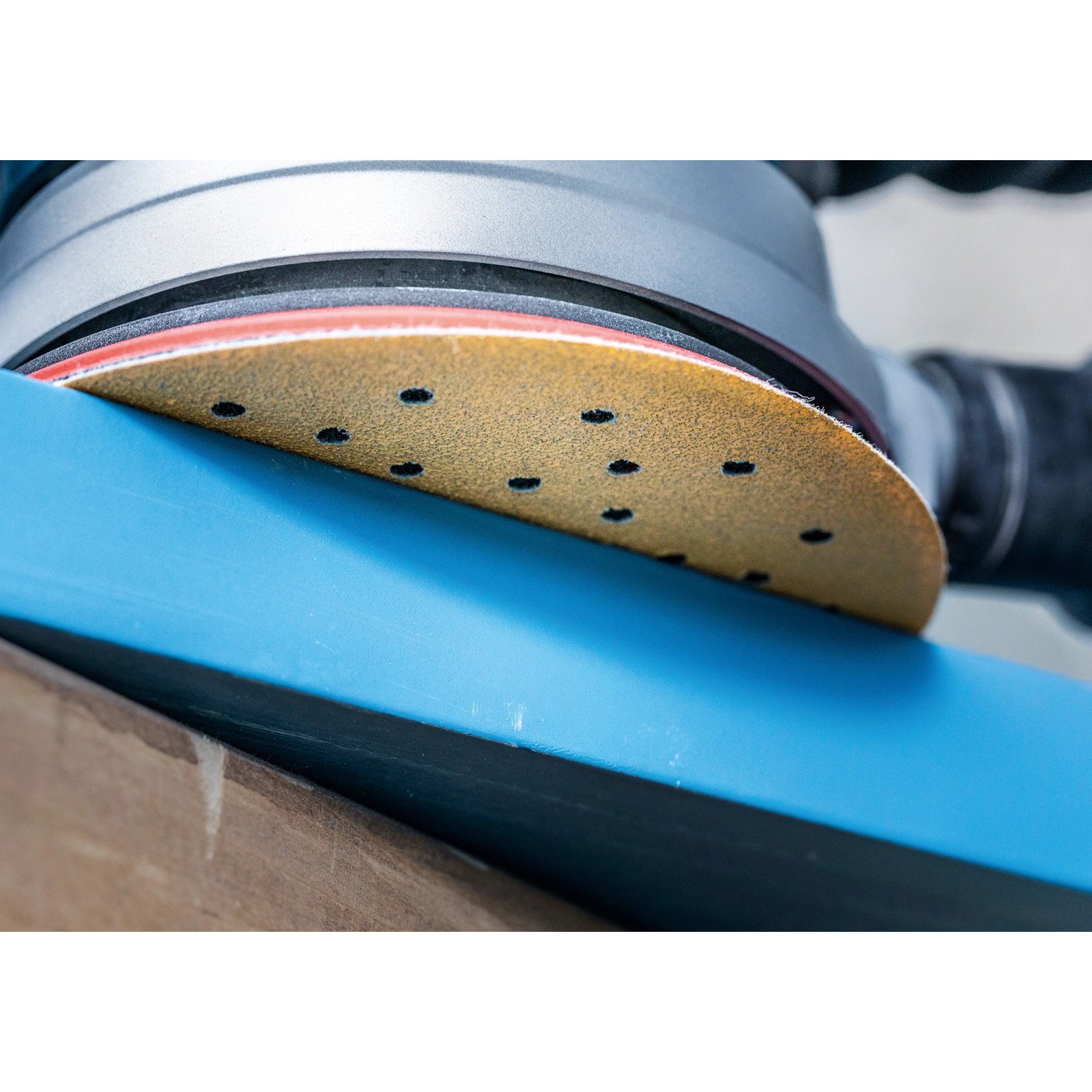Bosch Expert Schleifblatt C470, Ø 125 mm, K120, 5 Stück im Einsatz auf blauem Untergrund.
