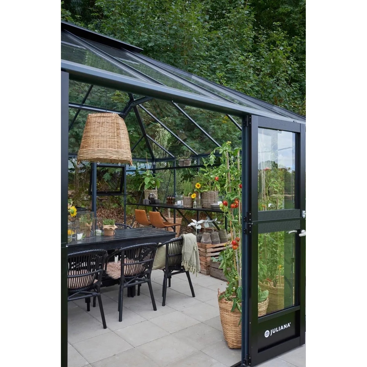 Juliana Gewächshaus Grand Oase 25, schwarz-anthrazit, mit Esstisch und Pflanzen.