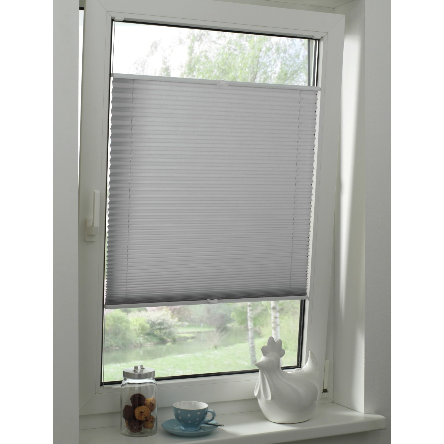 Graues Gardinia Plissee Concept Tageslicht am Fenster, flexibel verstellbar für optimalen Lichteinfall.