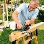 Mann hobelt Holz mit dem Bosch Hobel PHO 3100 im Garten. Hobel & Fräsen für Heimwerker.