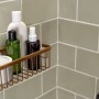 Tesa Moon Duschkorb in Bronze mit Shampoo und Duschgel an grauer Wand.
