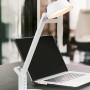 Weiße LED-Tischleuchte Ava von Trio mit USB-Anschluss vor Laptop.