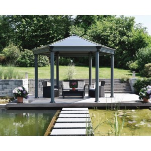 Anthrazitfarbener Palram Canopia Gartenpavillon Roma 4.1 x 3.6 m mit Sitzgruppe am Teich.