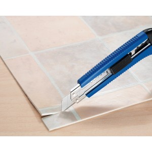 Blaues LUX Cuttermesser Classic 100 mm schneidet PVC-Bodenbelag auf Fliesenmuster Untergrund.